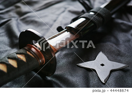 黒い布の上の抜きかけた日本刀と手裏剣の写真素材