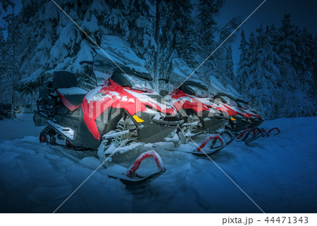 Polar night landscape with row of red snowmobiles 44471343