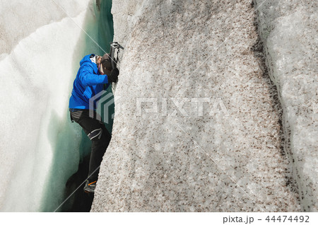 A free climber without insurance with two ice axes rises from a crack in the glacier. Free climbing A free climber without insurance with two ice axes rises from a crack in the glacier. Free climbing 44474492