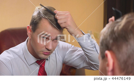 the concept of metrosexualism. a handsome man in front of a mirror takes care of his face. does the 44476149