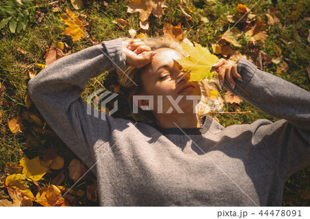 Young woman lying in autumn park with leafs. 44478091