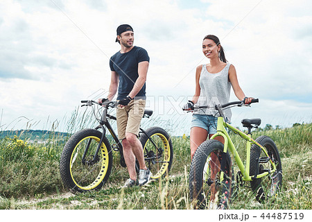 Young man looks at young beautiful woman with fatbike 44487519