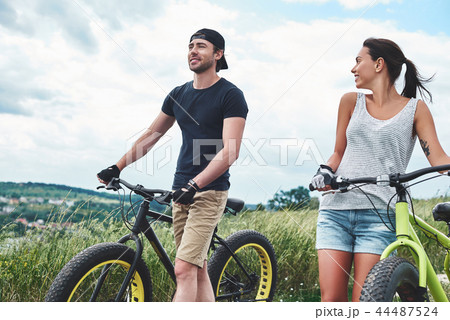 Young couple resting after bike ride in field Young couple resting after bike ride in field 44487524