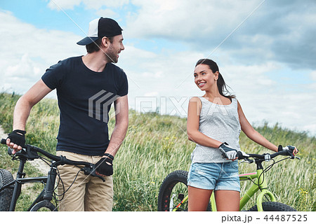 Young man looks at young beautiful woman with fatbike. Close up Young man looks at young beautiful woman with fatbike. Close up 44487525