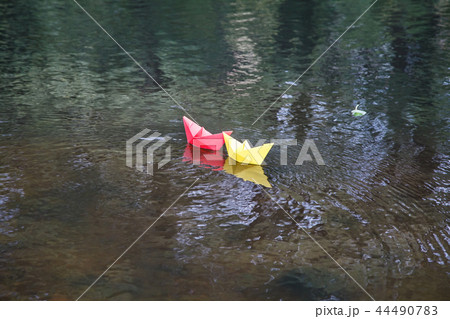 two multicolored paper boats floating on a stream 44490783