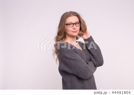 Smart beautiful young woman in glasses wearing grey oversize sweater on white background with copy Smart beautiful young woman in glasses wearing grey oversize sweater on white background with copy 44491804