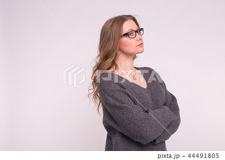 Emotions and people concept - Young woman on a white background with copy space in a grey knitting 44491805