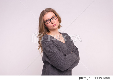 Emotions and people concept - Young woman on a white background in a grey knitting sweater hugging Emotions and people concept - Young woman on a white background in a grey knitting sweater hugging 44491806