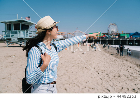 a pretty female tourist standing on the beach 44492253