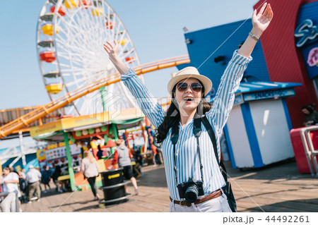 joyful female traveler raising arms to the sky 44492261