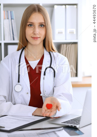 Female doctor with stethoscope holding heart in her arms. Healthcare and cardiology concept  i 44493670