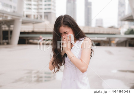 Woman sneeze on street because pollution 44494043
