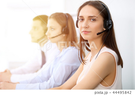 Call center operators. Focus on young cheerful smiling woman in headset. Business and customer 44495842