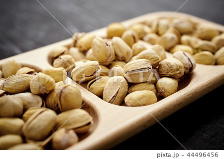 delicious pistachios on a wooden plate on an old black table 44496456