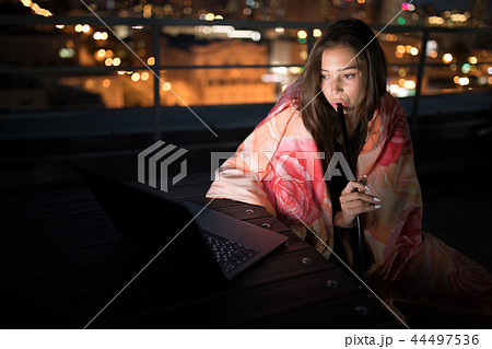 Girl sits wrapped in a blanket and smokes a hookah. 44497536