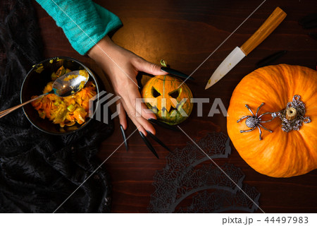 Photo of man's hands with pumpkin jack, spider, knife sitting at wooden table Photo of man's hands with pumpkin jack, spider, knife sitting at wooden table 44497983