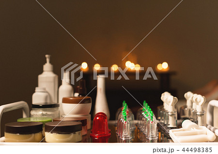 Medical set of glass jars and piston vacuum massage in a dark room amid burning candles Medical set of glass jars and piston vacuum massage in a dark room amid burning candles 44498385