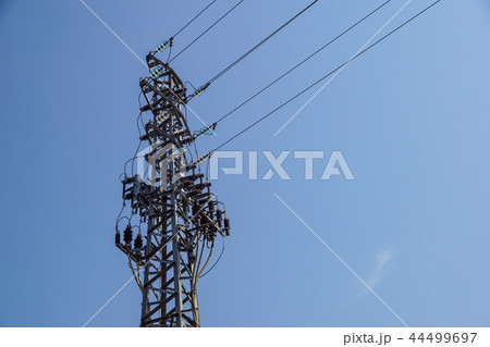 Lattice-type steel tower fragment over blue sky as a part of high-voltage line. Overhead power line Lattice-type steel tower fragment over blue sky as a part of high-voltage line. Overhead power line 44499697