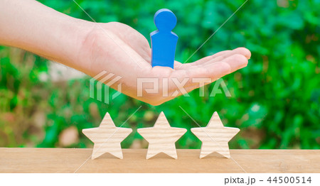 The hand holds a human figure and three stars. 44500514