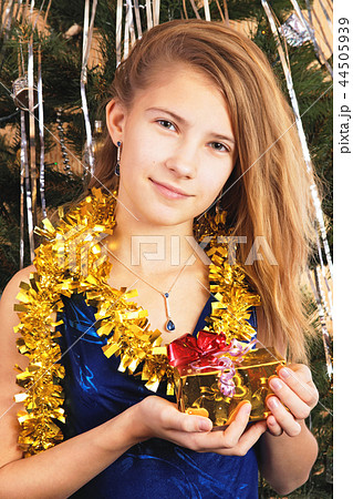 Beautiful happy teen girl holds before itself a Christmas gift Beautiful happy teen girl holds before itself a Christmas gift 44505939