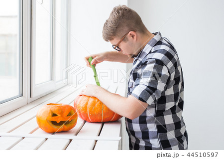 Halloween pumpkin cutting process. Handsome man making Jack-o-lantern. Halloween pumpkin cutting process. Handsome man making Jack-o-lantern. 44510597