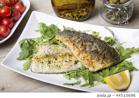 Grilled seabass fillet with arugula, lemon 44513696