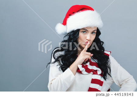 Young woman with Santa hat making a quiet gesture Young woman with Santa hat making a quiet gesture 44519343