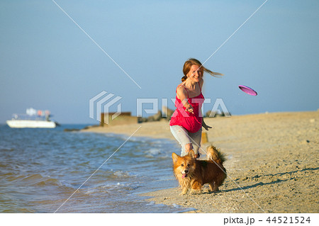 girl playing with a dog on the beach 44521524