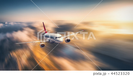 White airplane is flying in low clouds at sunset 44523320