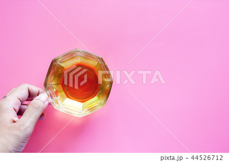 Hand holding cup of tea on pink background 44526712