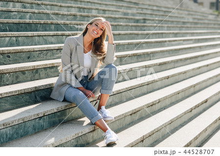 Beautiful young blonde woman smiling on urban steps. 44528707