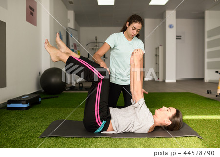 Physical therapist assisting young caucasian woman with exercise 44528790