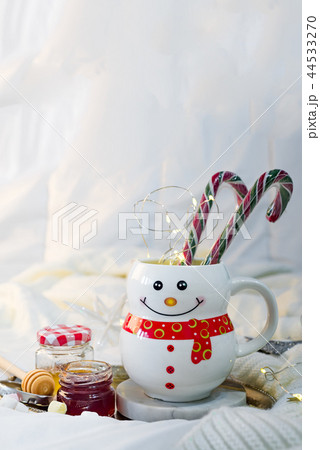 cozy soft blanket with a cup in the form of a snowman with Christmas candies, honey and jam on the cozy soft blanket with a cup in the form of a snowman with Christmas candies, honey and jam on the 44533270