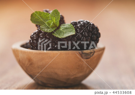 fresh blackberries in wood bowl on wooden table with mint leaves 44533608