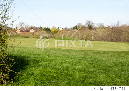 冬のゴルフ場 白い旗が立つグリーンと遠くに見えるレンガ造りの家並み 冬のゴルフ場 白い旗が立つグリーンと遠くに見えるレンガ造りの家並み 44534741