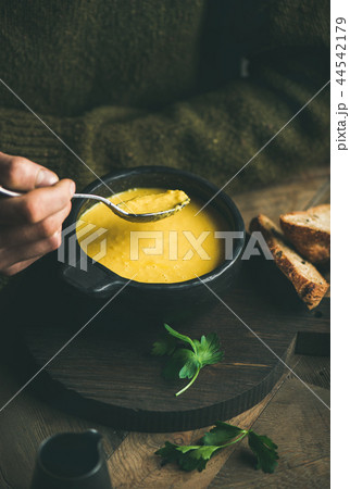 Man in dark sweater eating sweet corn soup with bread Man in dark sweater eating sweet corn soup with bread 44542179