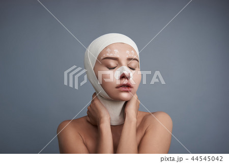 Young lady wearing bandages and closing her eyes 44545042