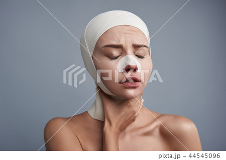 Sad woman touching her neck while recovering after plastic surgery 44545096