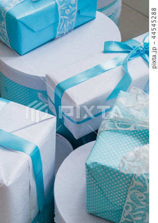 Christmas gift boxes with blue bow and bokeh lights on wooden surface Christmas gift boxes with blue bow and bokeh lights on wooden surface 44545288