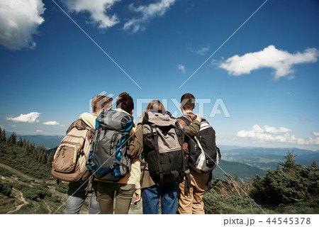 Four backpackers are observing highland view from top Four backpackers are observing highland view from top 44545378