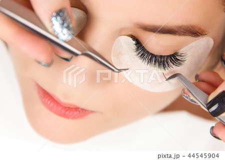 Eyelash Extension Procedure. Woman Eye with Long Eyelashes. Close up, selective focus. Eyelash Extension Procedure. Woman Eye with Long Eyelashes. Close up, selective focus. 44545904