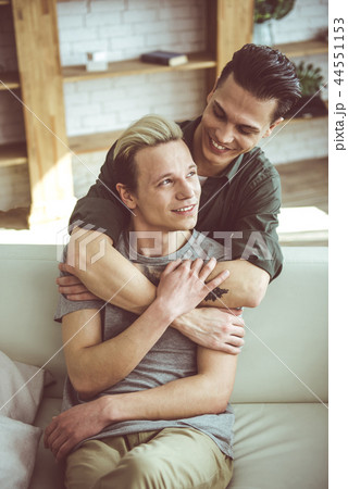 Happy gay couple cuddling while spending time at home Happy gay couple cuddling while spending time at home 44551153