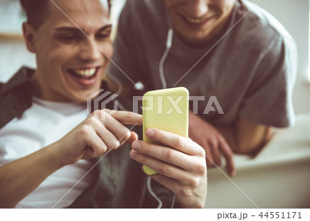 Two handsome guys watching videos on smartphone and smiling Two handsome guys watching videos on smartphone and smiling 44551171