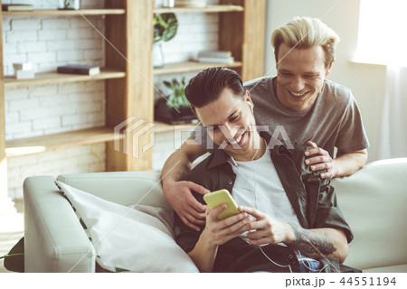 Young gay couple watching videos on smartphone at home Young gay couple watching videos on smartphone at home 44551194