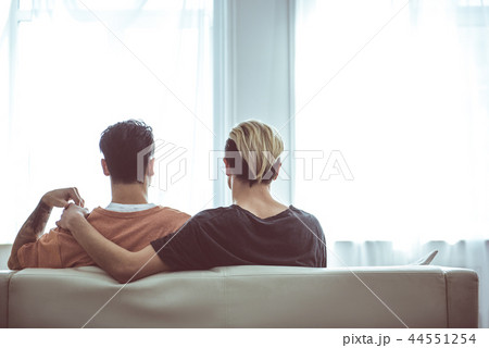 Happy gay couple cuddling while sitting on couch 44551254