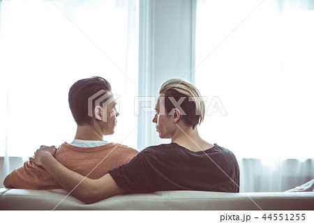 Gay couple looking at each other while sitting on couch 44551255
