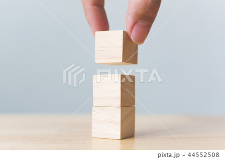 Hand arranging wood block stacking on top 44552508