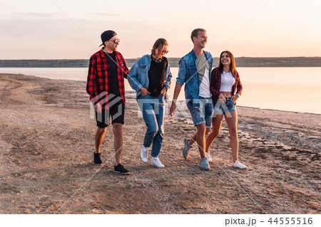 friends on beach together walking during sunset friends on beach together walking during sunset 44555516
