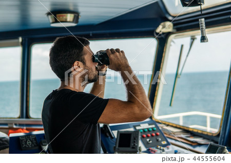 Navigational officer lookout on navigation watch looking through binoculars Navigational officer lookout on navigation watch looking through binoculars 44555604