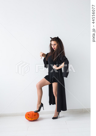 Halloween and masquerade concept - Beautiful young woman posing with Pumpkin Jack-o'-lantern. 44556077